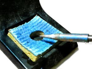 Cleaning a soldering iron with a wet sponge